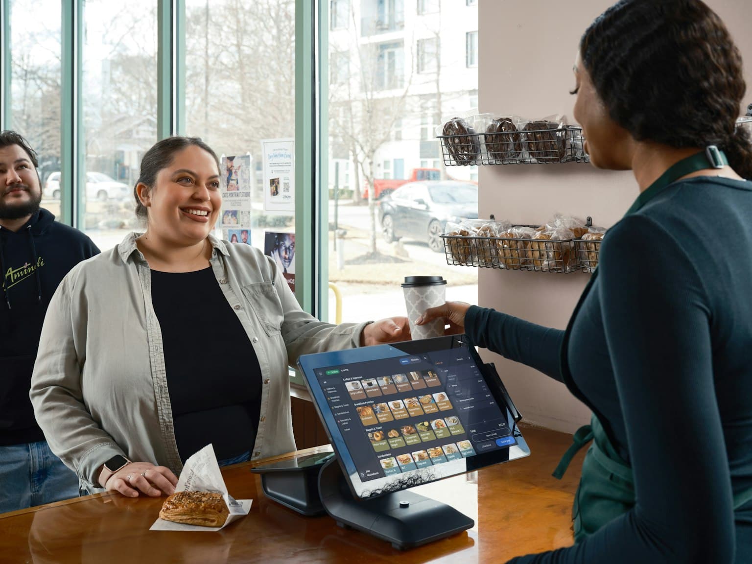 Café staff serving a smiling customer at the counter